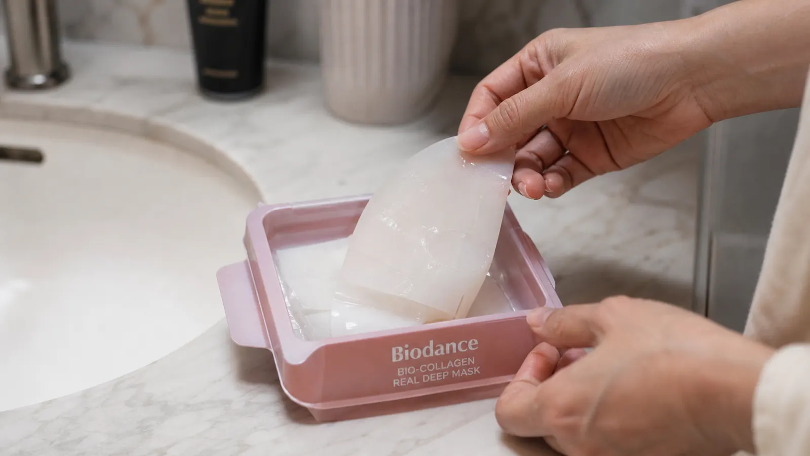 Hands peeling open a BIODANCE PDRN Real Deep Mask packaging and lifting out the hydrogel disc